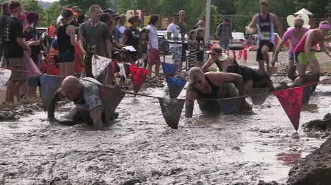 Runners running and crawling through mud pit in obstacle endurance race Stock Footage 40064744