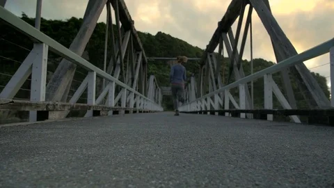 Running away over bridge at sunset, eerie, scared, exercise Stock Footage 79996054