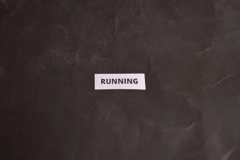 Running concept paper note on black textured background with minimalist desig Fotos Stock