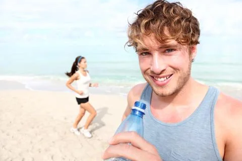 Running couple - Man runner drinking water smiling happy Foto stock