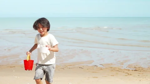 Running cute boy playing water and sand outside on the beach together Stock Footage 199265812