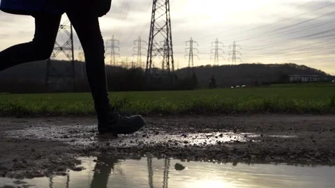 Running female stepping in solid boots into puddle and splashing water Video stock 157007535