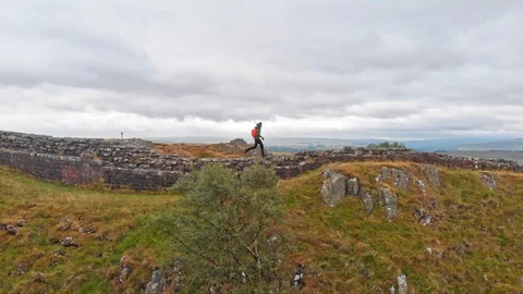 Running on Hadrian's wall side drone shot Stock Footage 125796490