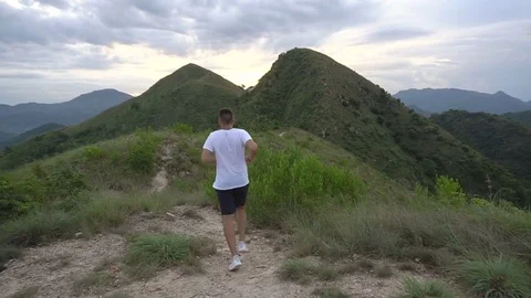 Running man exercising on mountain forest trail at sunset. Male run, work out Stock Footage 76512642