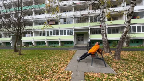Running man in orange waterproof jacket resting on the bench. Runner is dressed Stock Footage 337800328