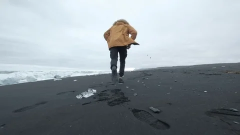 Running a man in a picturesque natural landscape on the running ocean in Iceland Stock Footage