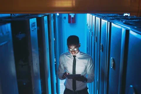 This is running much better. a young IT specialist standing alone in the server 写真素材
