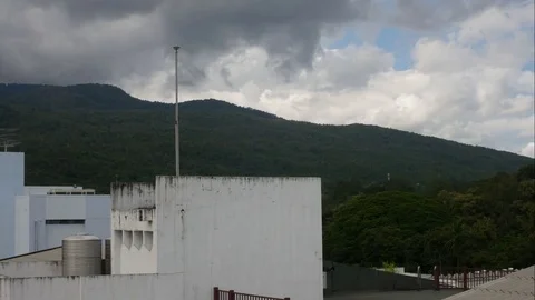 Running rain cloud over the buildings with mountain background Stock Footage 81402659
