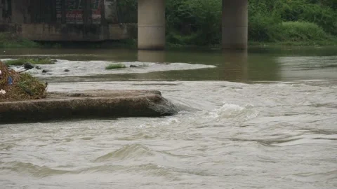A running river , pillars in the river at a distance, big rock in the middle Stock Footage 225739703