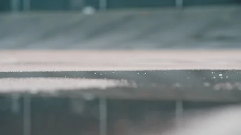 Running shoe hitting puddle on wet all weather track Stock Footage 96087897