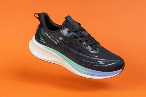 Running shoe levitating on orange background. Modern athletic footwear for .. Stock Photos