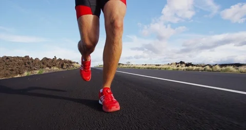 Running shoes on male triathlete runner - close up of feet running on road Stock Footage
