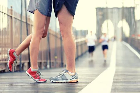 Running shoes runners in love kissing on Brooklyn bridge during marathon race Stock Photos