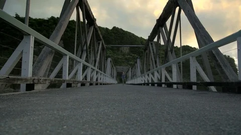 Running towards camera over bridge at sunset, eerie, scared, exercise Stock Footage 79996123