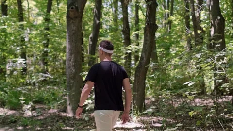Running training program in a forest setting. A man runs in the park, smiles at Stock Footage 280186337