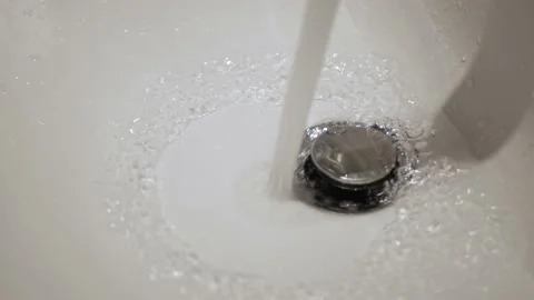 Running water flows from the tap to the white sink Stock Footage 208940060