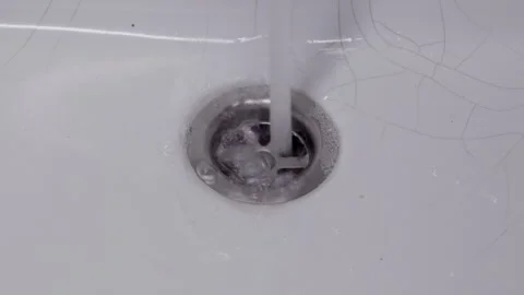 Running Water Washing Soap Bubbles Down Chrome Bathroom Sink Drain Video stock 328523662