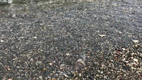 Running wave dangles from pebbles Stock Photos