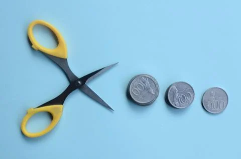 Rupiah Decrease Concept. Rupiah coins and scissors. Coins with blue background 스톡 사진