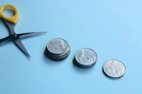 Rupiah Decrease Concept. Rupiah coins and scissors. Coins with blue background Stock Photos