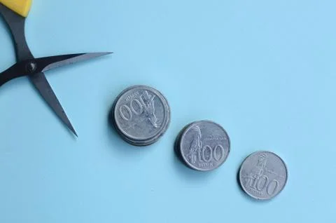 Rupiah Decrease Concept. Rupiah coins and scissors. Coins with blue background 스톡 사진