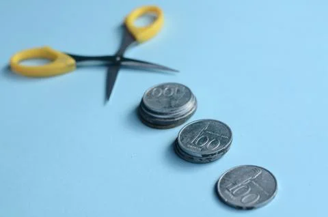 Rupiah Decrease Concept. Rupiah coins and scissors. Coins with blue background 스톡 사진