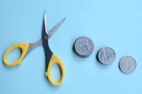 Rupiah Decrease Concept. Rupiah coins and scissors. Coins with blue background 스톡 사진