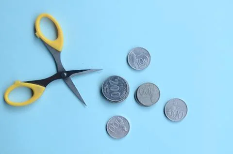 Rupiah Decrease Concept. Rupiah coins and scissors. Coins with blue background 스톡 사진