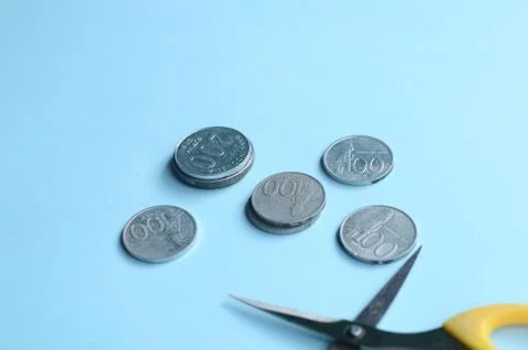 Rupiah Decrease Concept. Rupiah coins and scissors. Coins with blue background Stock Photos