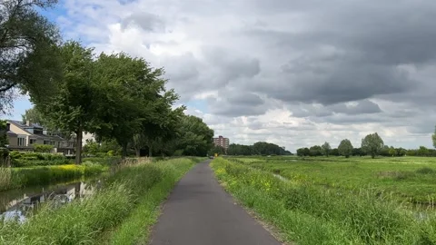 Rural Amsterdam, Riverside cycle path through Dutch meadow under dramatic Stock Footage 342751190