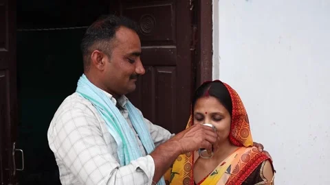 Rural Indian husband lovingly offering a glass of water to his wife, expres.. Stock Footage 335119417