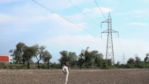 Rural Indian man talking on mobile phone under high-voltage electricity tra.. Stock-Footage 335119696