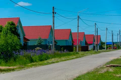 Rural landscape, along the road are identical houses with red roofs. Stock Photos