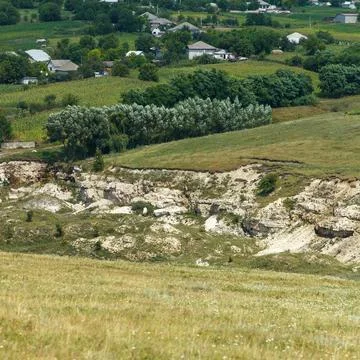 Rural landscape with eroded limestone cliffs and distant village houses in .. Foto stock