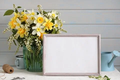 Rural mockup with an empty frame and a bouquet of daffodils and cherry trees Foto stock