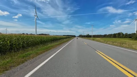 Rural Motorcycle Ride Past Cornfields and Wind Turbines Beneath a Blue Sky 스톡 동영상 345510490