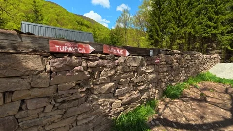 Rural path winds beside ancient stone wall. Tupavica Waterfall, trail marker. Stock Footage 335532472