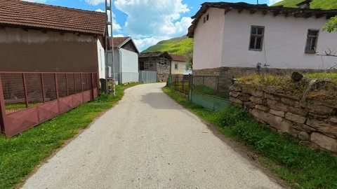 Rural path winds past rustic buildings. Dojkinci village, Serbia Stock Footage 335534133