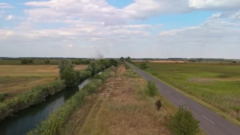 Rural road and reed-lined canal through summer fields near Újsolt, Hungary Stock Footage 346664262