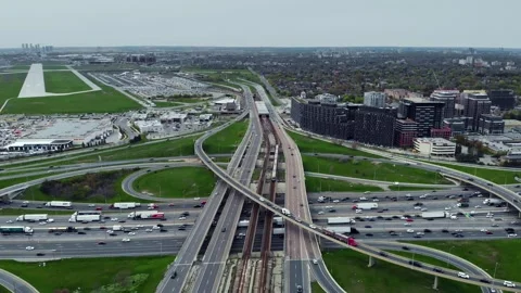 Rushing metro train parallels highway traffic, cars zip by, aerial captures Stock Footage 273378452