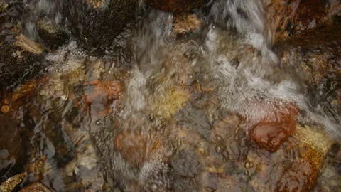 Rushing mountain stream flowing over colorful rocks Stock Footage 331798879
