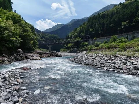 Rushing river flows over rocky bed Stock Photos