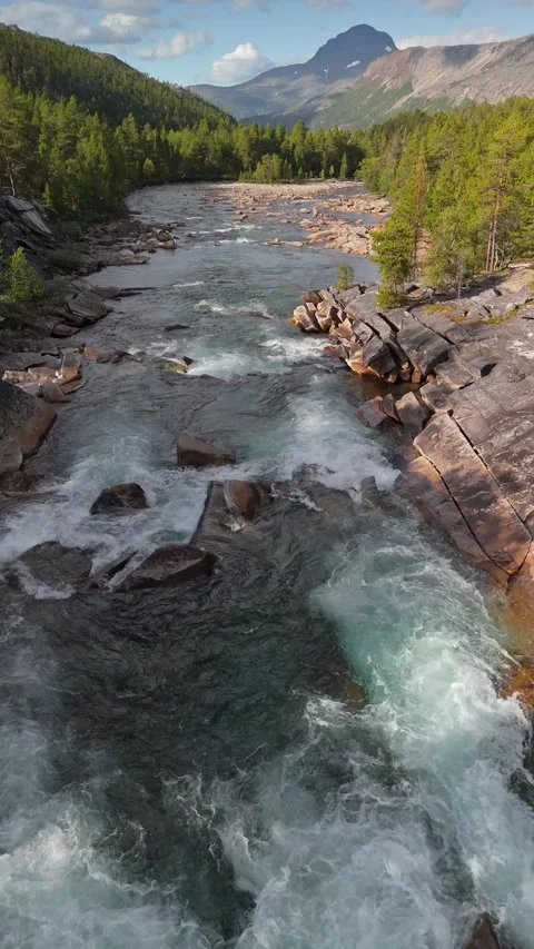 Rushing river flows through rocky landscape in mountain region. Flying over a Stock Footage 323523921