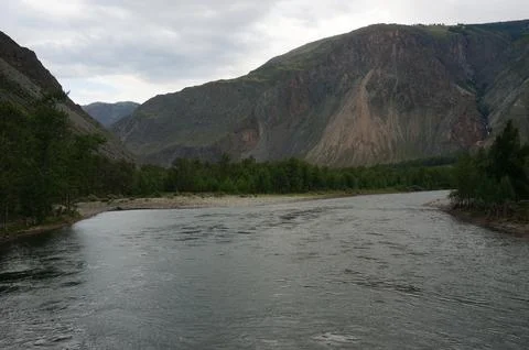 A rushing river flows through a valley at the bottom of a canyon Stock Photos