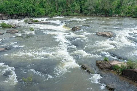 Rushing river rapids flow over rocky terrain surrounded by lush tropical fore Stock Photos