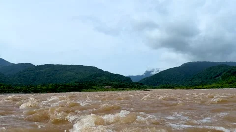 Rushing river with turbulent waters flowing through lush green hills under .. Stock-Footage 339295908