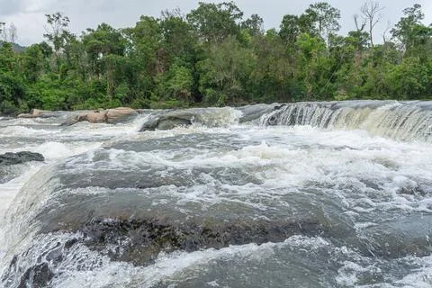 Rushing river water cascading over rocky rapids through a dense tropical ra.. Stock Photos