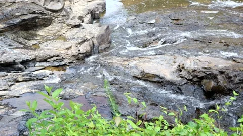 Rushing water flows across the bottom of a rocky creek bed, 4k Stock Footage 337434858