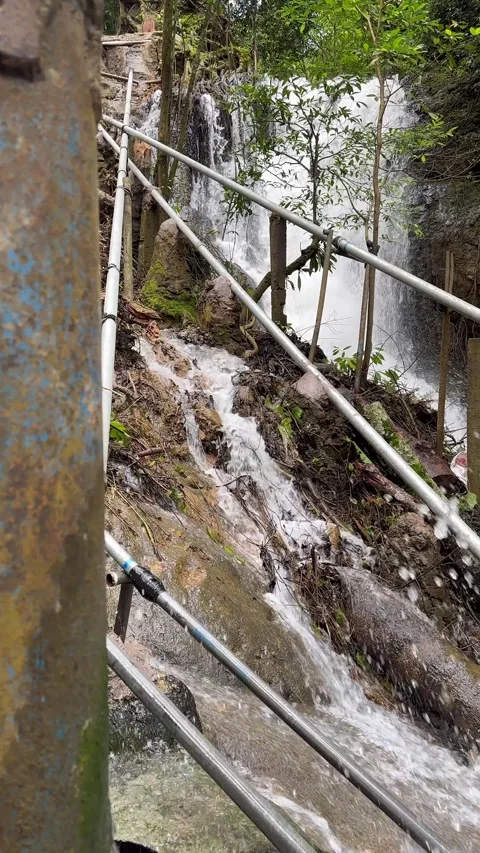 Rushing Waterfall Cascading Down Rocky Slope with Handrails, Vertical Shot Stock Footage 325304346