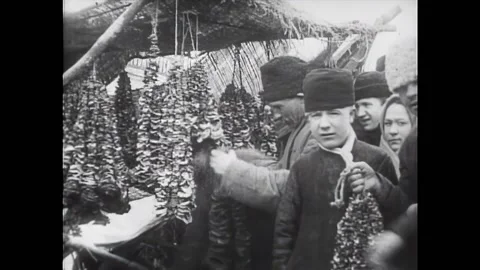 RUSSIA - 1909 - People hold strings of mushrooms at a market. Women buy things Stock Footage 327742140